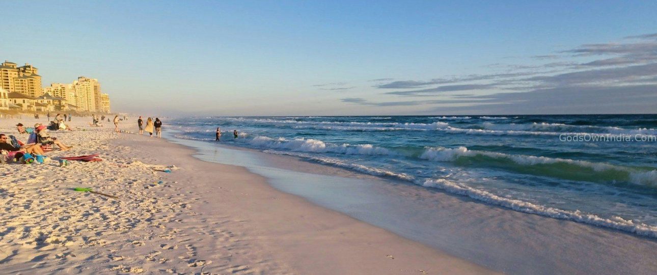 a beach with people walking on the sand and in the water