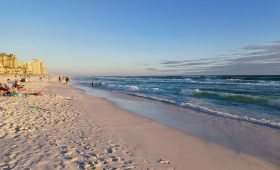 a beach with people walking on the sand and in the water