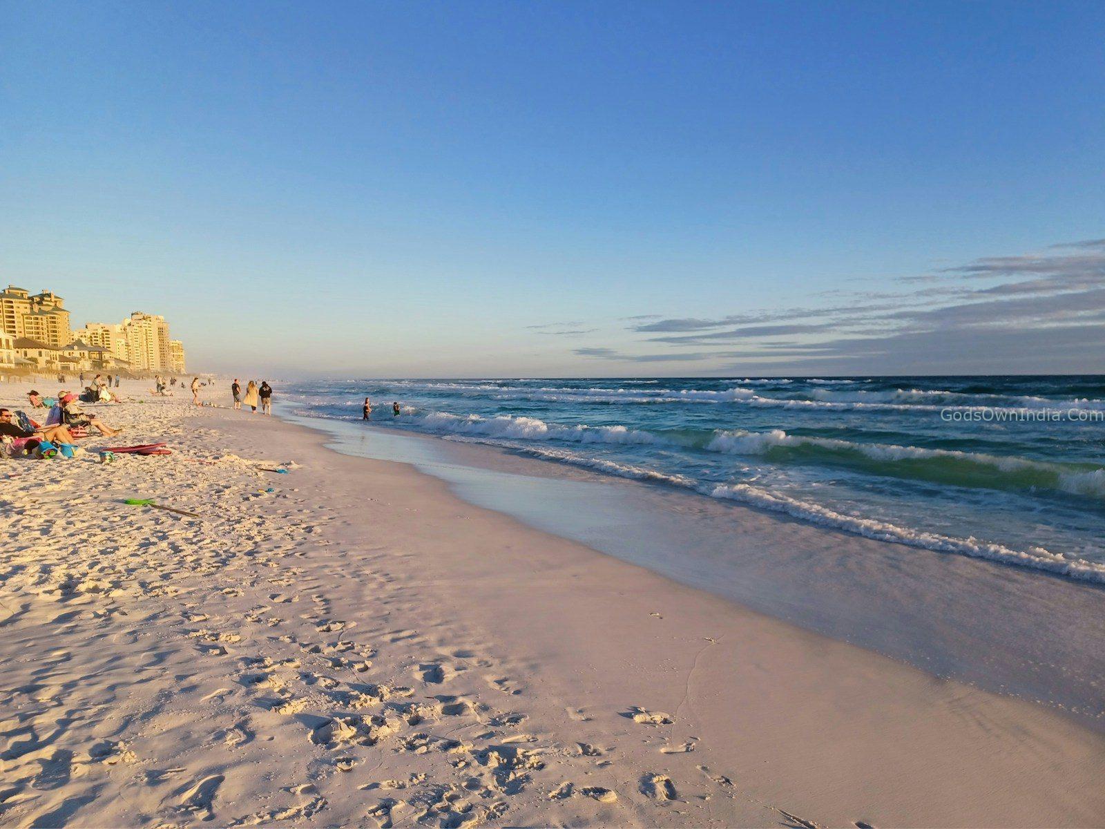 a beach with people walking on the sand and in the water