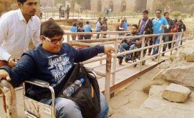 A group including wheelchair users crossing a bridge at a historic site