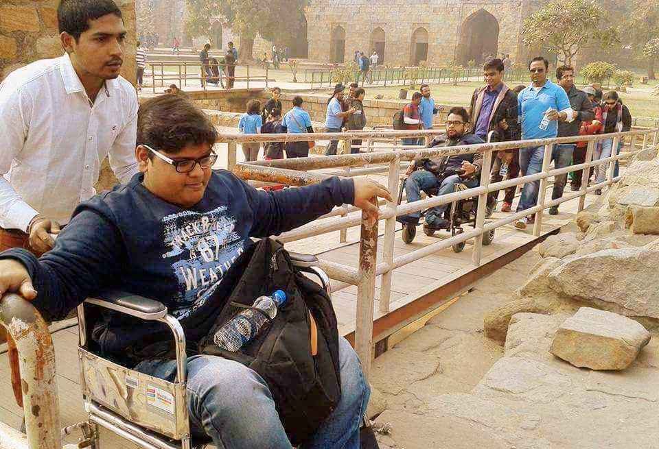 A group including wheelchair users crossing a bridge at a historic site