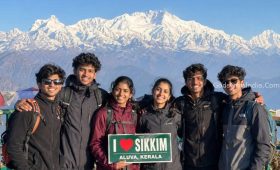 A group of young Indian travelers (age 18-20, appearing to be from Aluva, Kerala) standing at a viewpoint in Sikkim
