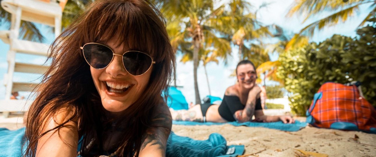 a woman laying on top of a blue towel on top of a beach