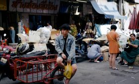 a man sitting on a red cart in front of a store