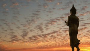 a statue of a person standing in front of a sunset